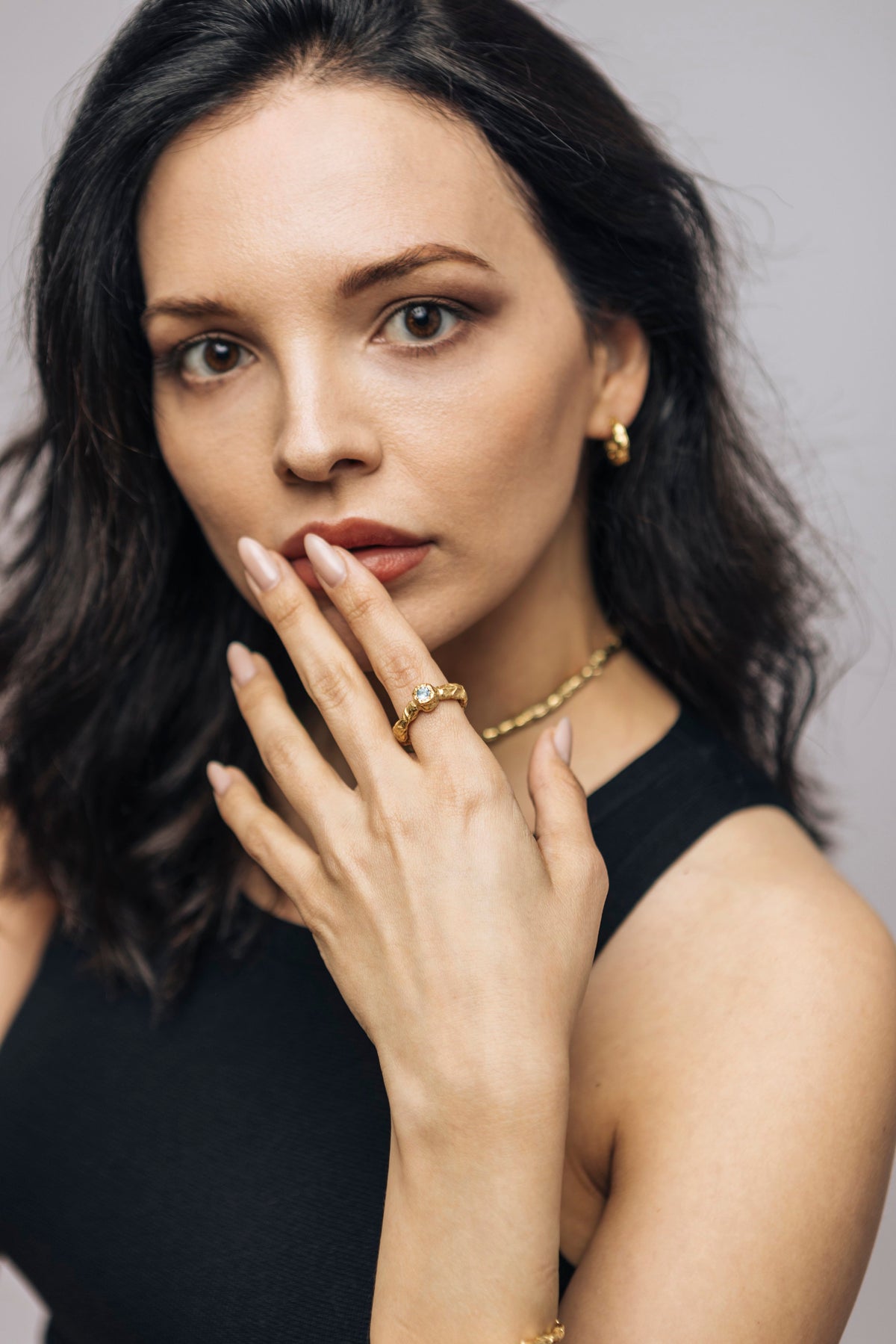 Model wearing a gold Origen Choker and a Galaxia ring with a blue topaz, by Bocavolcan