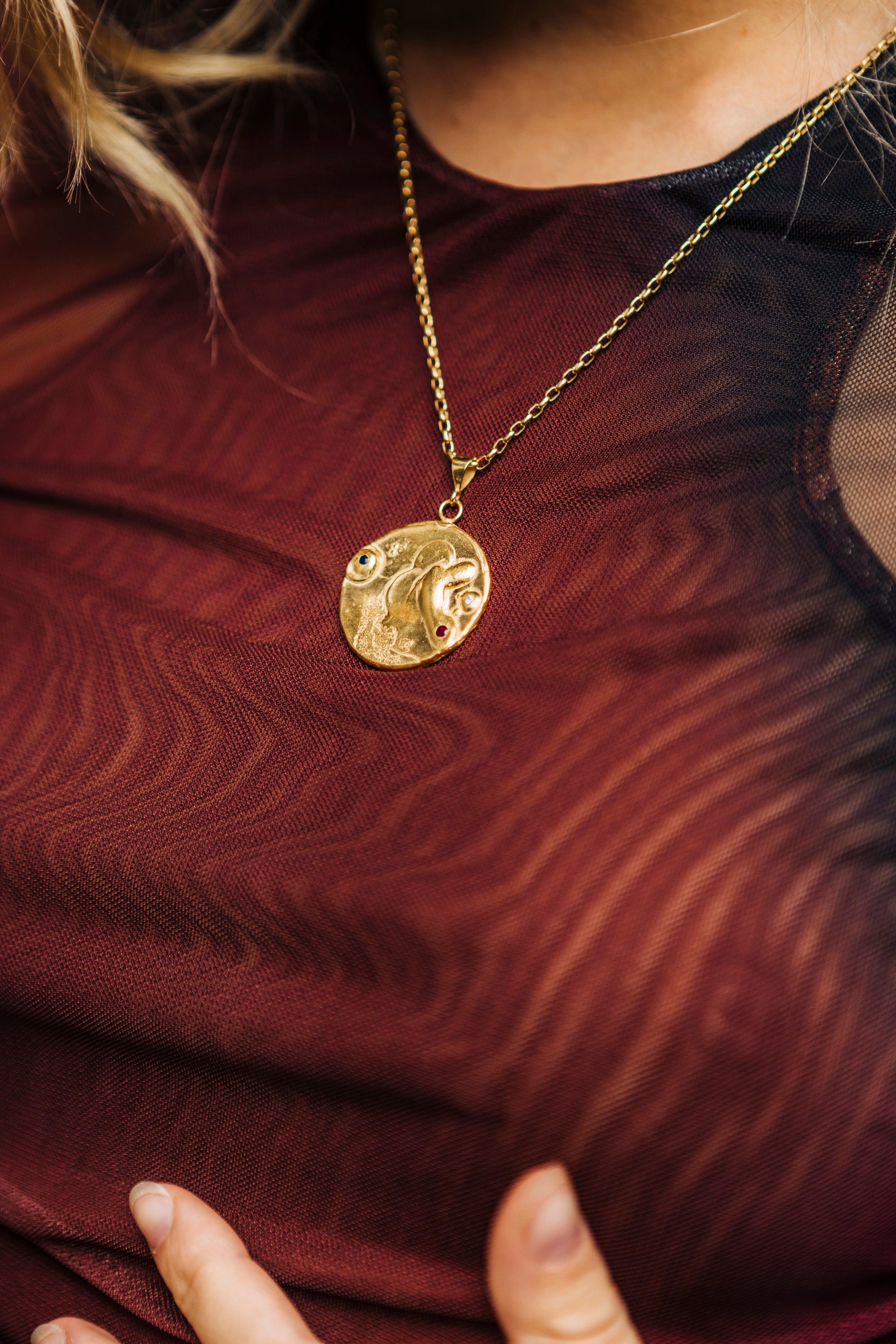 Closeup of Bocavolcan's Gold Plated 925 Silver Lahar necklace with Sapphire Ruby and Blue Sky Topaz stones "Lahar" necklace handcrafted in Valencia, Spain with a background of volcanic rocks